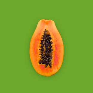 Picture of a papaya cut in half looking directly above it showing the seeds inside on a green background.